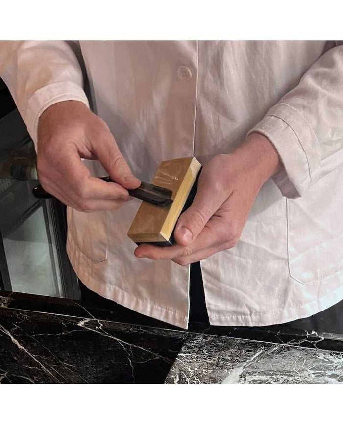 Person using Coticule water stone for shaving prep
