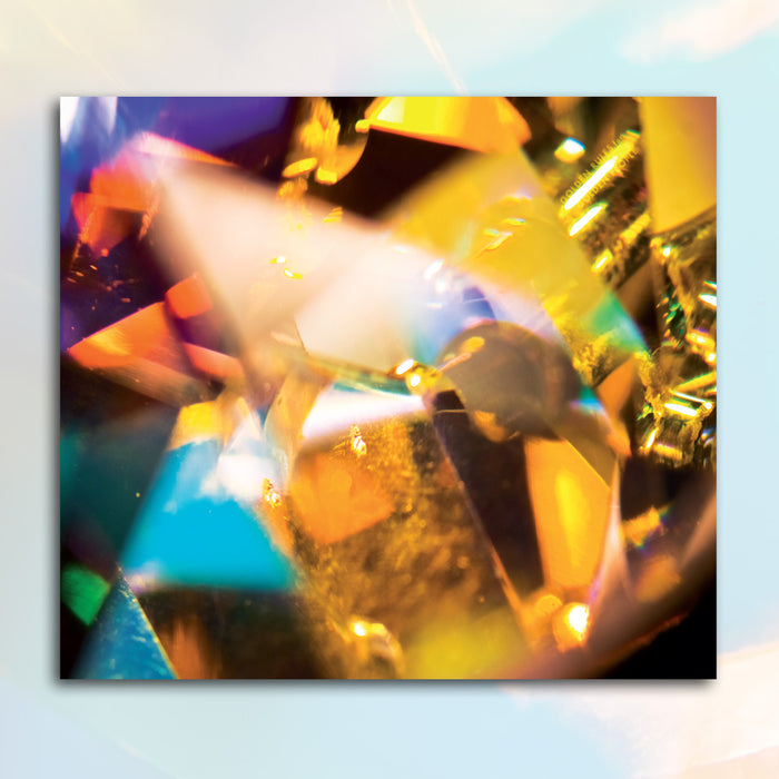 Colorful abstract image of light refracting through a faceted surface, creating vibrant yellow, orange, blue, and purple hues—like Pretty & Nice music dancing across a soft, blurred background in bright, overlapping shapes.