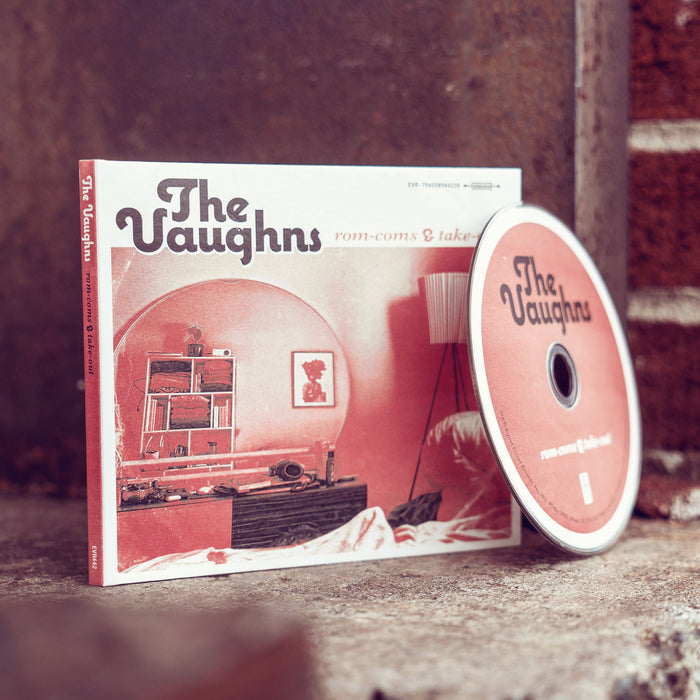 Square CD with The Vaughns written in the top left corner in black font. To the right of that, there is smaller red text that says rom-coms & takeout. The album art is a drawing of a 70's living room with a large rounded arch in the center. The drawing is done in white, black, and red. A CD disc is leaning up against the cover. The disc is the same red color as the album.