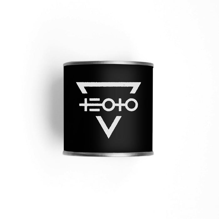 A black cylindrical The End Of The Ocean Aire Candle container with a silver rim displays a white geometric symbol—an upside-down triangle with a horizontal line and connected circles—set against a white background.