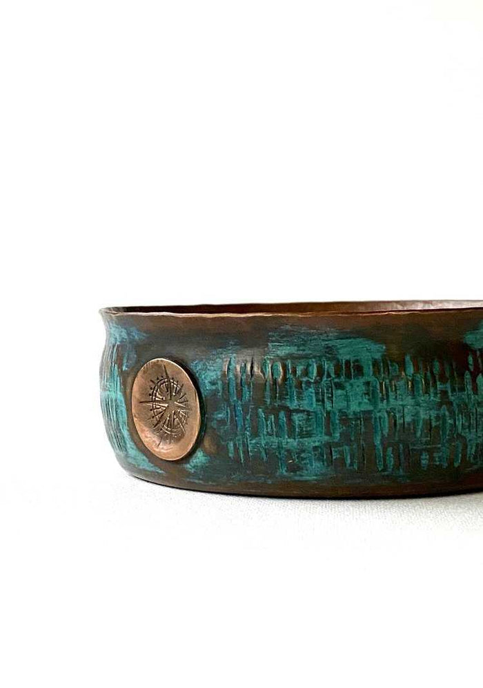 Bottom view of copper lather bowl showing embossed logo and textured aquamarine exterior, handcrafted from thick copper for grooming