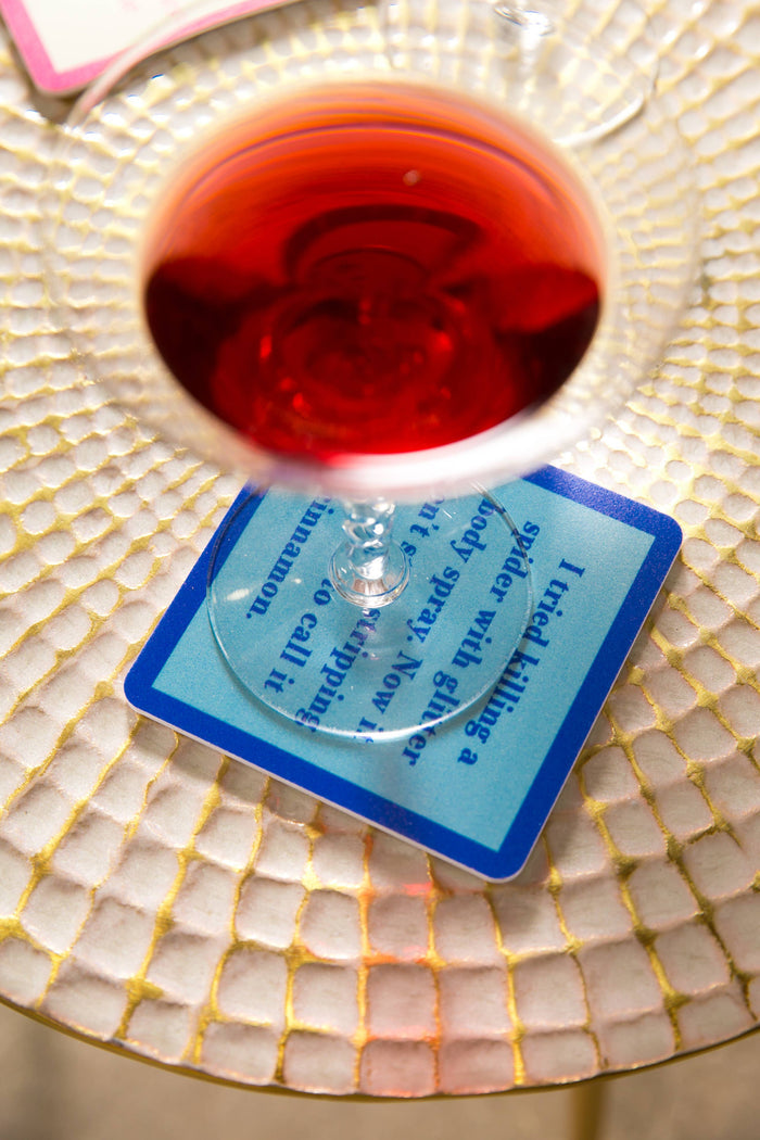Red wine glass on textured plate with coaster text.
