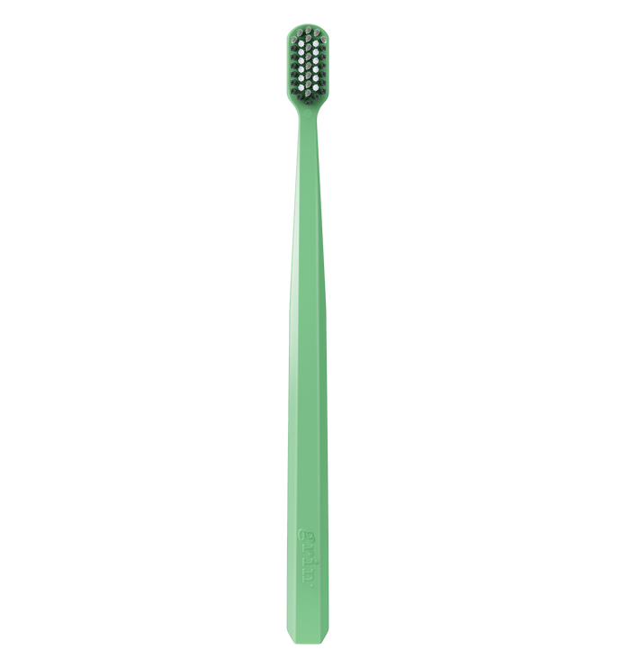 Grin Pro Ultimate Whitening Toothbrush in green with dark and white bristles, Grin logo embossed on handle, white background.