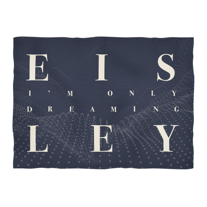 A cozy, dark blue Eisley blanket featuring “I’M ONLY DREAMING” in large cream letters across a subtle dotted wave pattern.