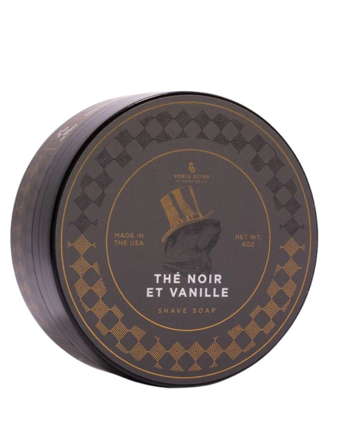 Noble Otter Thé Noir et Vanille shaving soap in a round black and gold tin with elegant geometric patterns and a top hat illustration