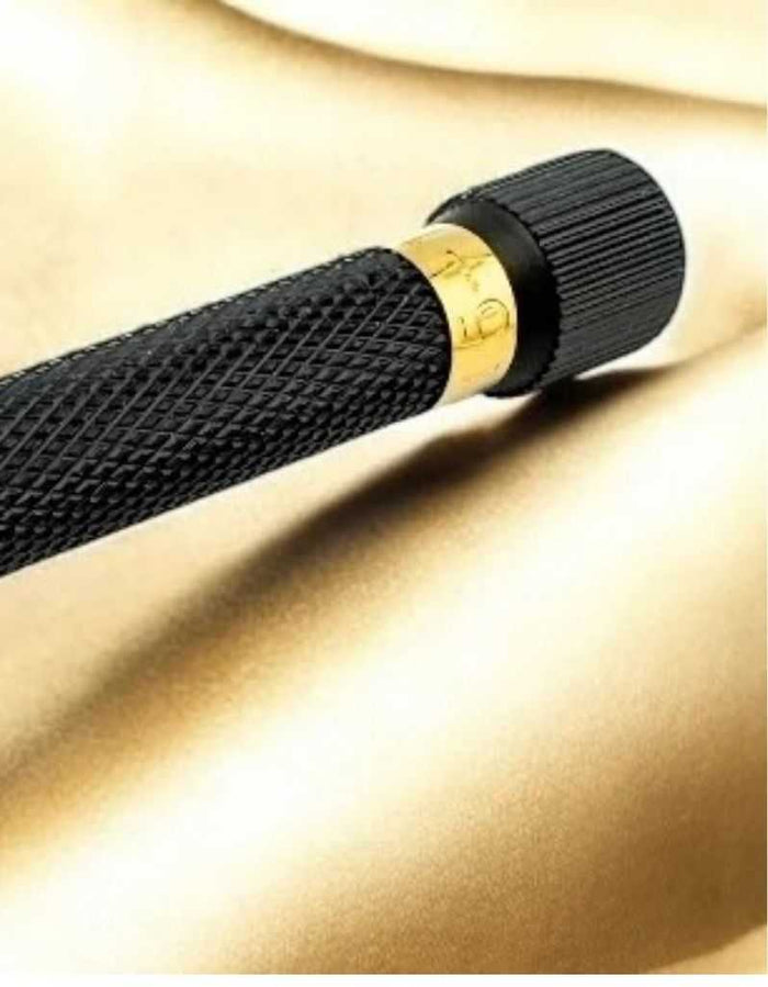 Close-up of textured black safety razor handle with gold accent