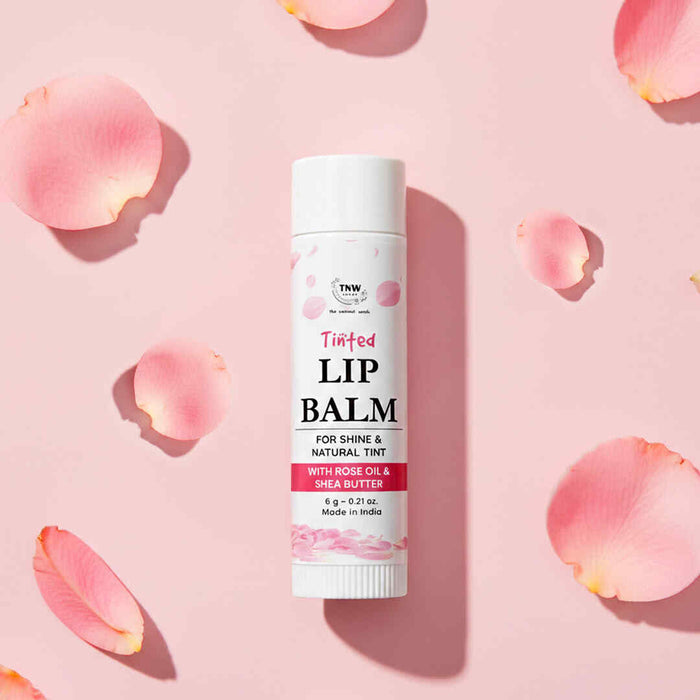 Lip balm tube on a pink background with rose petals