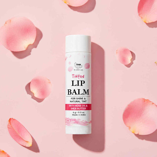 Lip balm tube on a pink background with rose petals