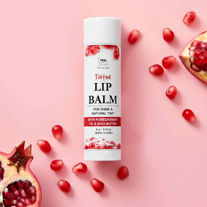 Lip balm with pomegranate seeds on a pink background