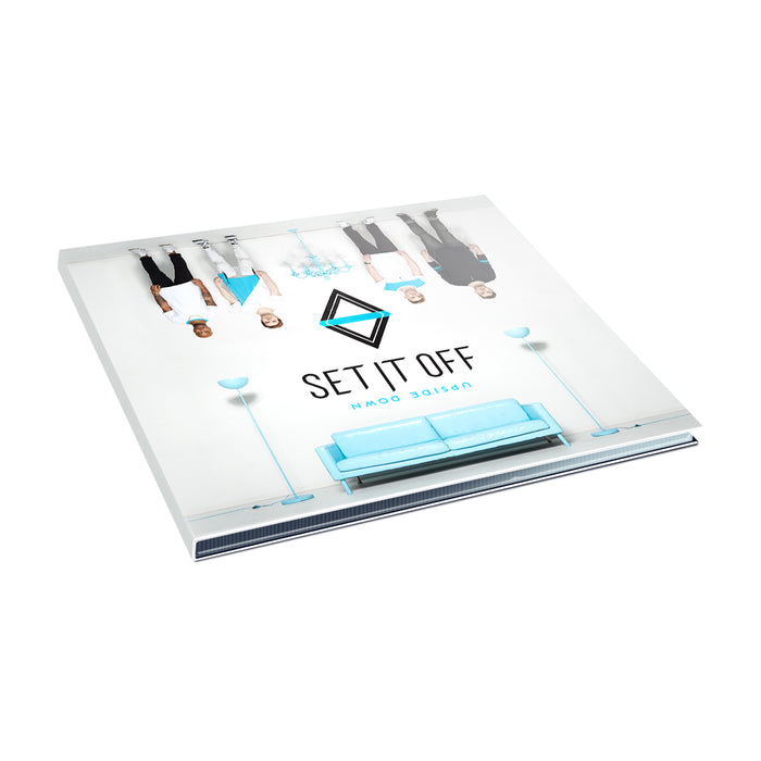 Set It Offs album Upside Down shows a blue couch, two lamps, and five people standing upside down on the cover, with the band’s name and CD title displayed prominently.
